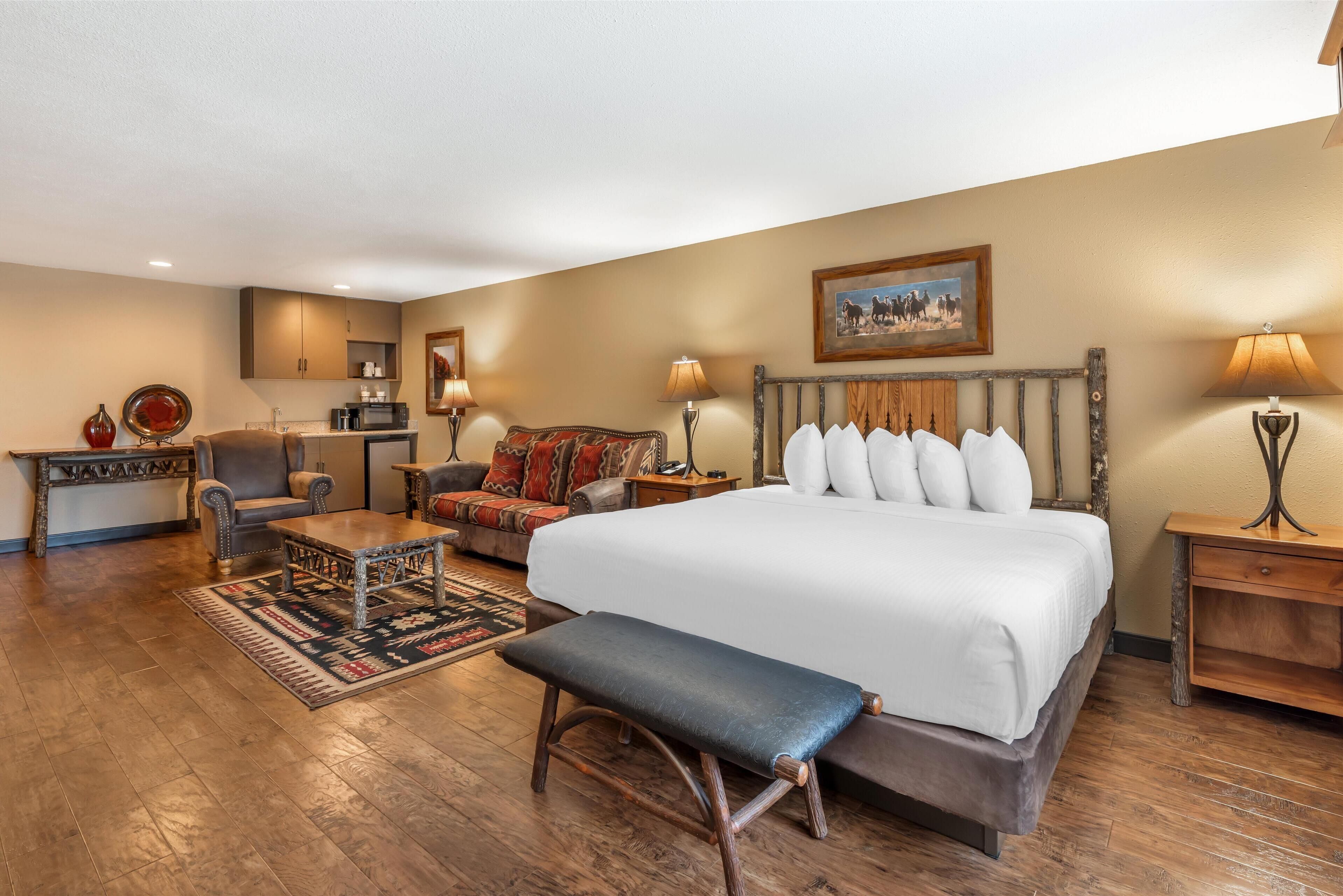 A spacious room with a large bed, a sofa, a small table, and a bench.