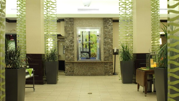 A spacious lobby with a high ceiling, modern pendant lighting, and a reception desk with a stone accent wall. - Hilton Garden Inn Frederick (Frederick)