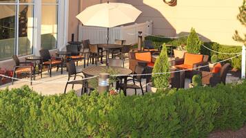 An outdoor patio with wicker furniture, a table, and an umbrella.