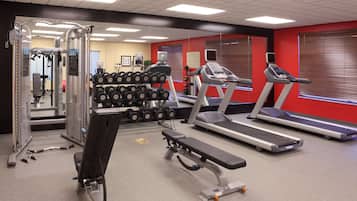 A gym with treadmills, dumbbells, and weight machines.