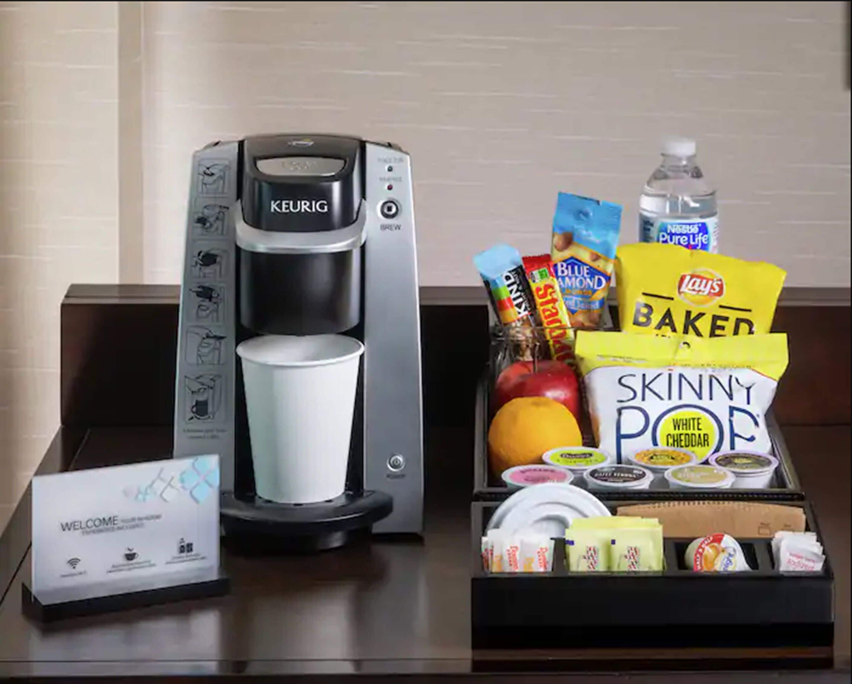 A coffee maker, a welcome sign, and a tray with snacks and condiments.