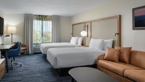 Habitación de hotel con dos camas, un escritorio, una silla, un sofá y un televisor.
