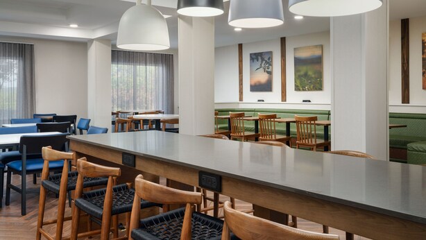 Un comedor moderno con una barra alargada, sillas de madera e iluminación colgante.