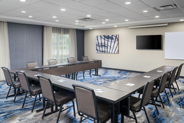 A conference room with a long table, chairs, a projector screen, and a whiteboard.