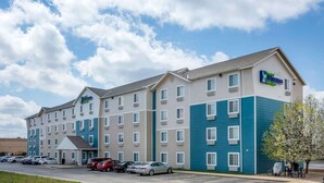 A multi-story hotel with a blue and beige exterior, multiple parking spaces, and a clear sky. - Extended Stay America Select Suites - Springfield - South - Battlefield (Springfield)