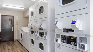 A laundry room with multiple washing machines and dryers, each with digital control panels. - Extended Stay America Select Suites - Springfield - South - Battlefield (Springfield)