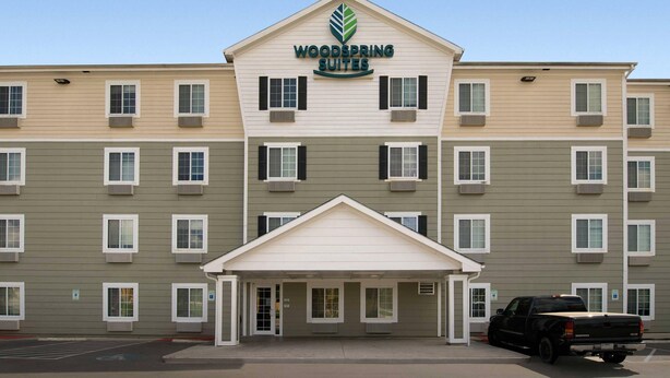 A multi-story hotel with a central entrance and a parking area. - WoodSpring Suites San Antonio Fort Sam (San Antonio)