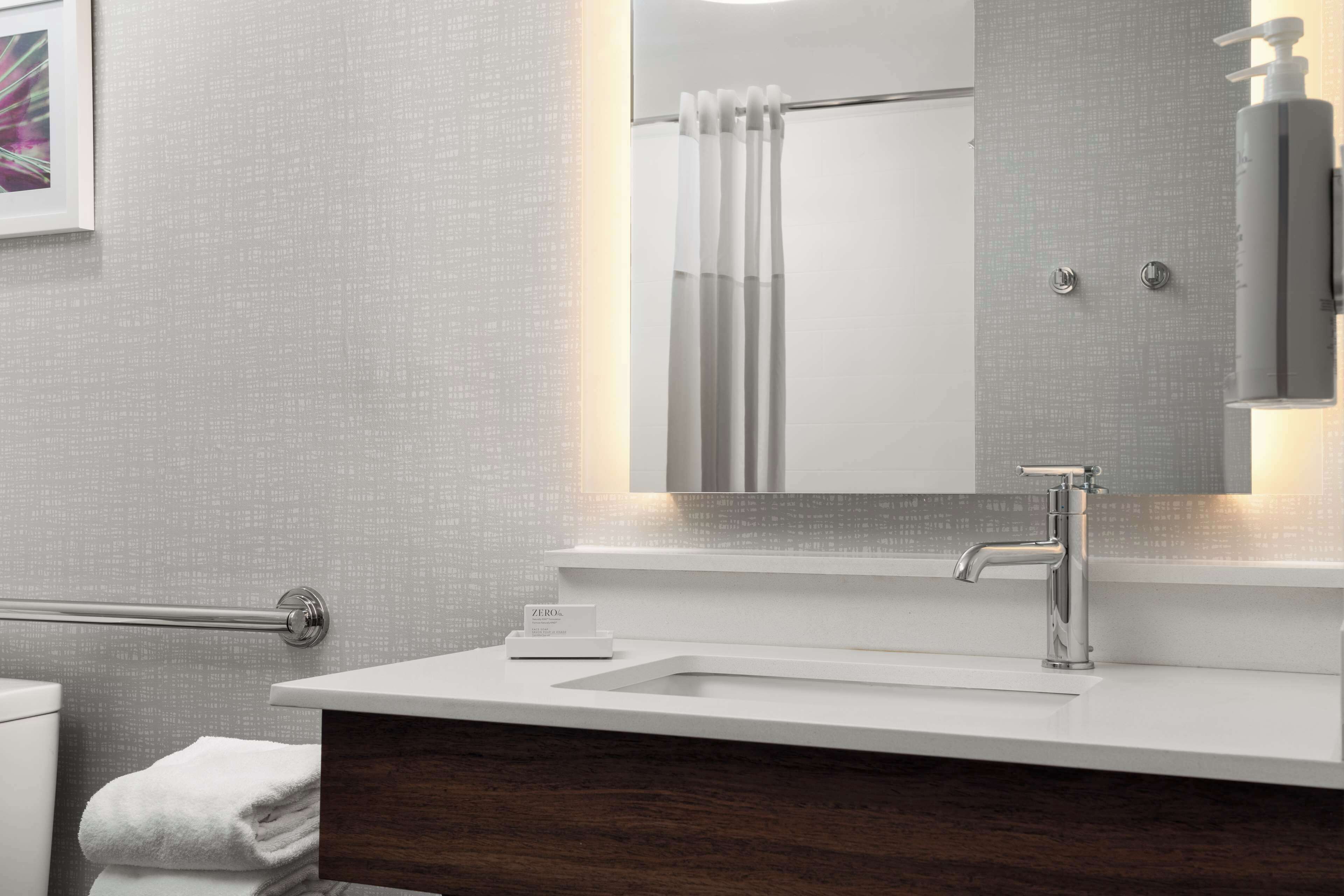 Une salle de bain moderne avec un meuble-lavabo blanc, un grand miroir et un porte-serviettes.