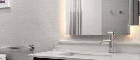 A modern bathroom with a white vanity, a large mirror, and a towel rack.