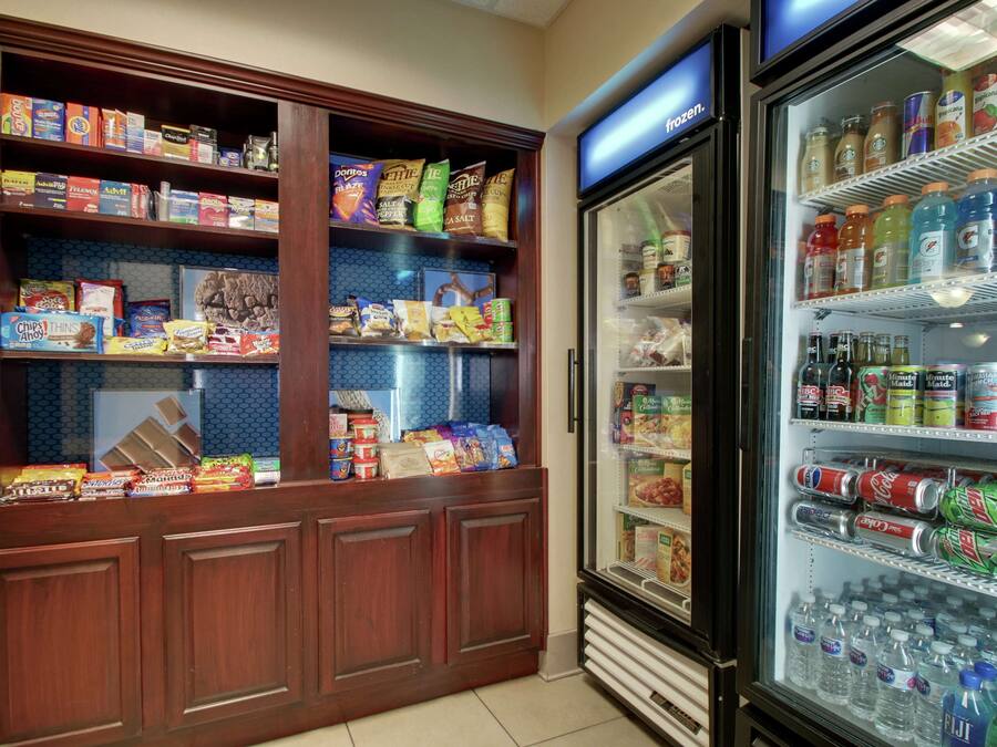 A snack and beverage display in a hotel lobby, including chips, snacks, and a variety of drinks.