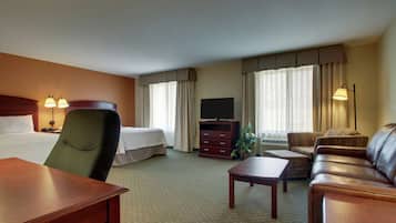Habitación de hotel con cama, escritorio, sofá, televisor y lámpara.