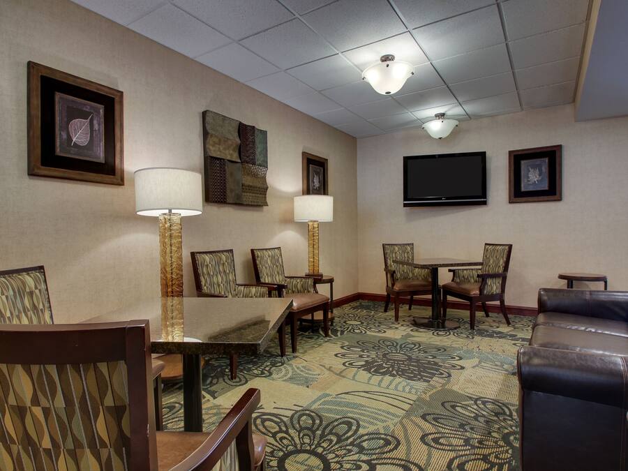 Habitación de hotel con una mesa de comedor, sillas, un sofá, un televisor y obras de arte en las paredes.