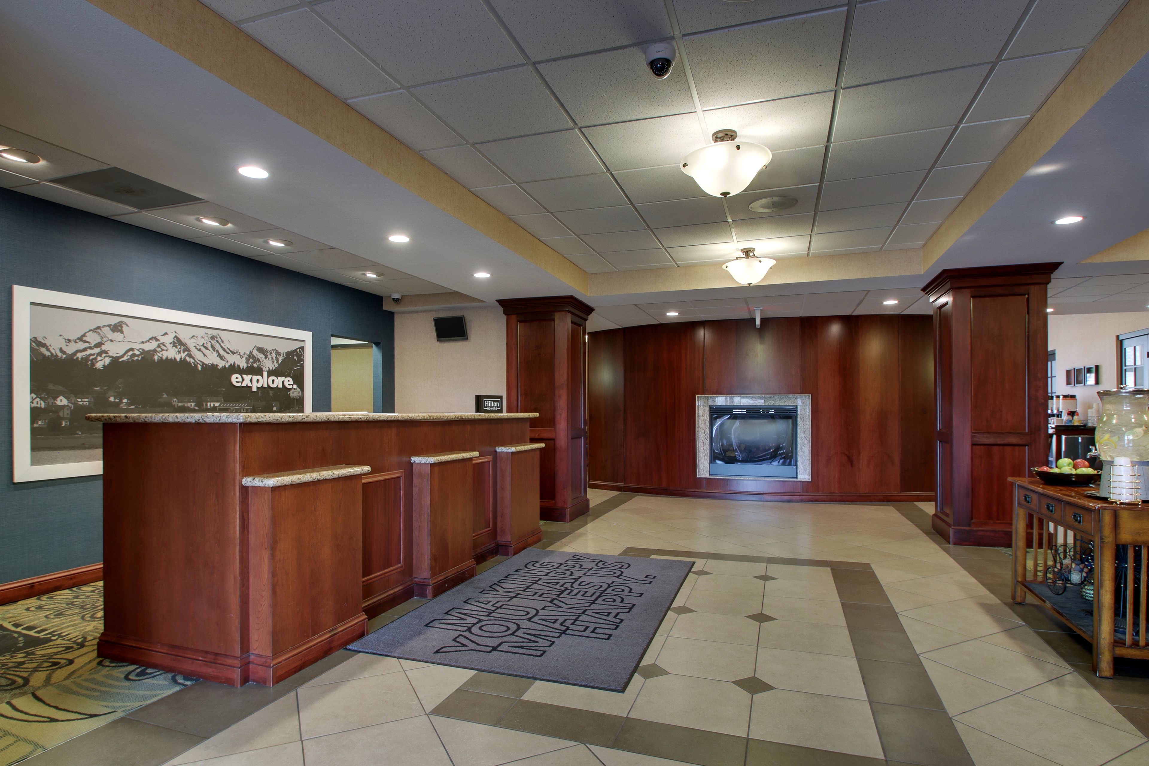 A lobby with a reception desk, a welcome mat, a fireplace, and a coffee station.