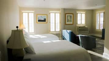 A hotel room with a large bed, a desk, a chair, and two windows.