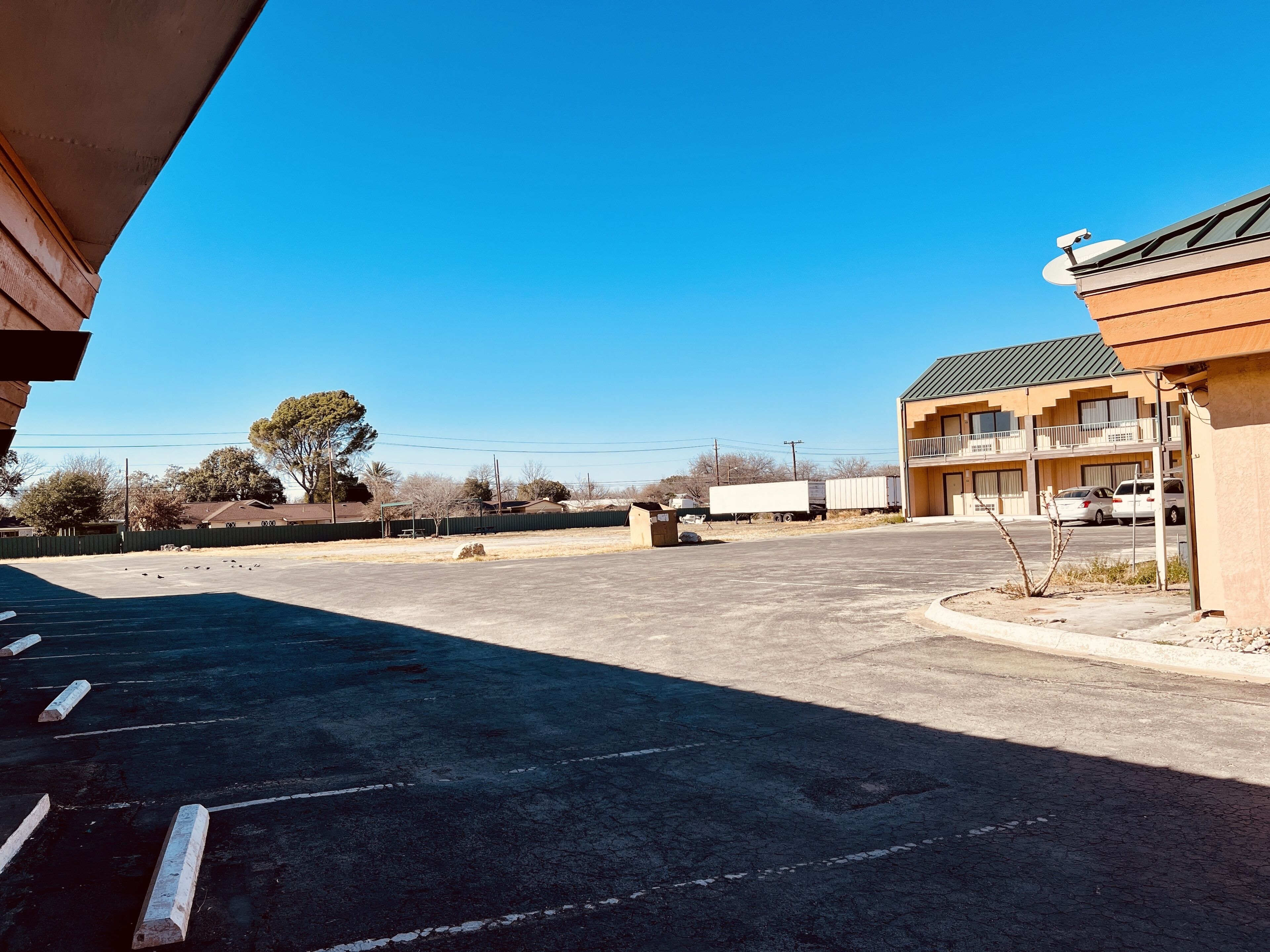 A parking lot with a building featuring a balcony on the right.
