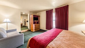 Une chambre d’hôtel comprenant un lit, un bureau, une chaise, une armoire et un miroir.