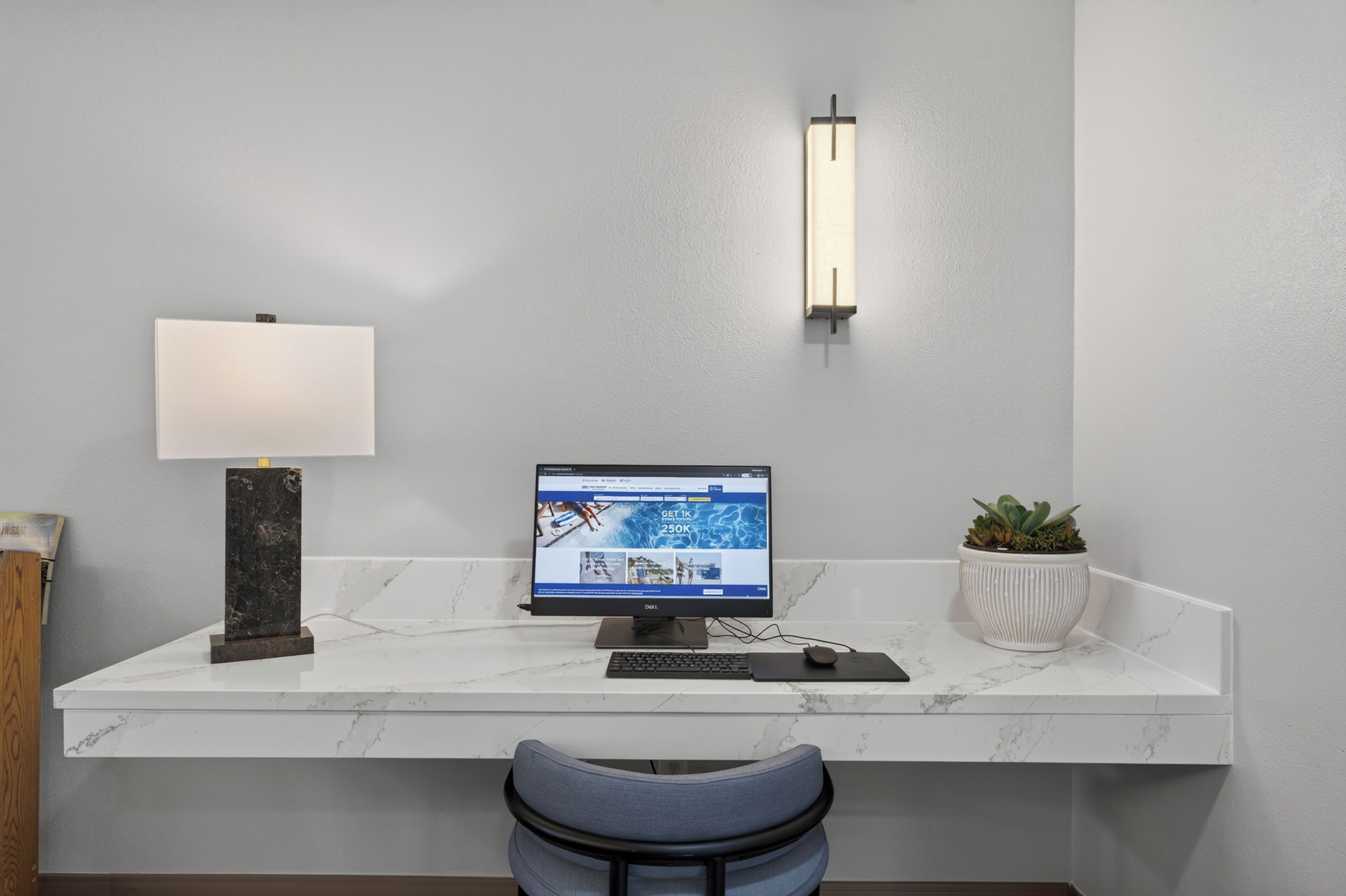 A modern desk with a computer, a lamp, and a potted plant.
