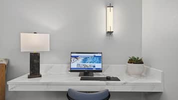 Een modern bureau met een computer, een lamp en een potplant.