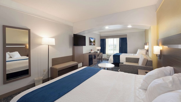 Une chambre d’hôtel avec un grand lit, un bureau, une chaise, une petite table et un téléviseur.