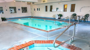 Une piscine intérieure bordée de briques, à l’eau claire, avec un drain central.