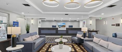 A modern lobby with sofas, a reception desk, and a patterned carpet.