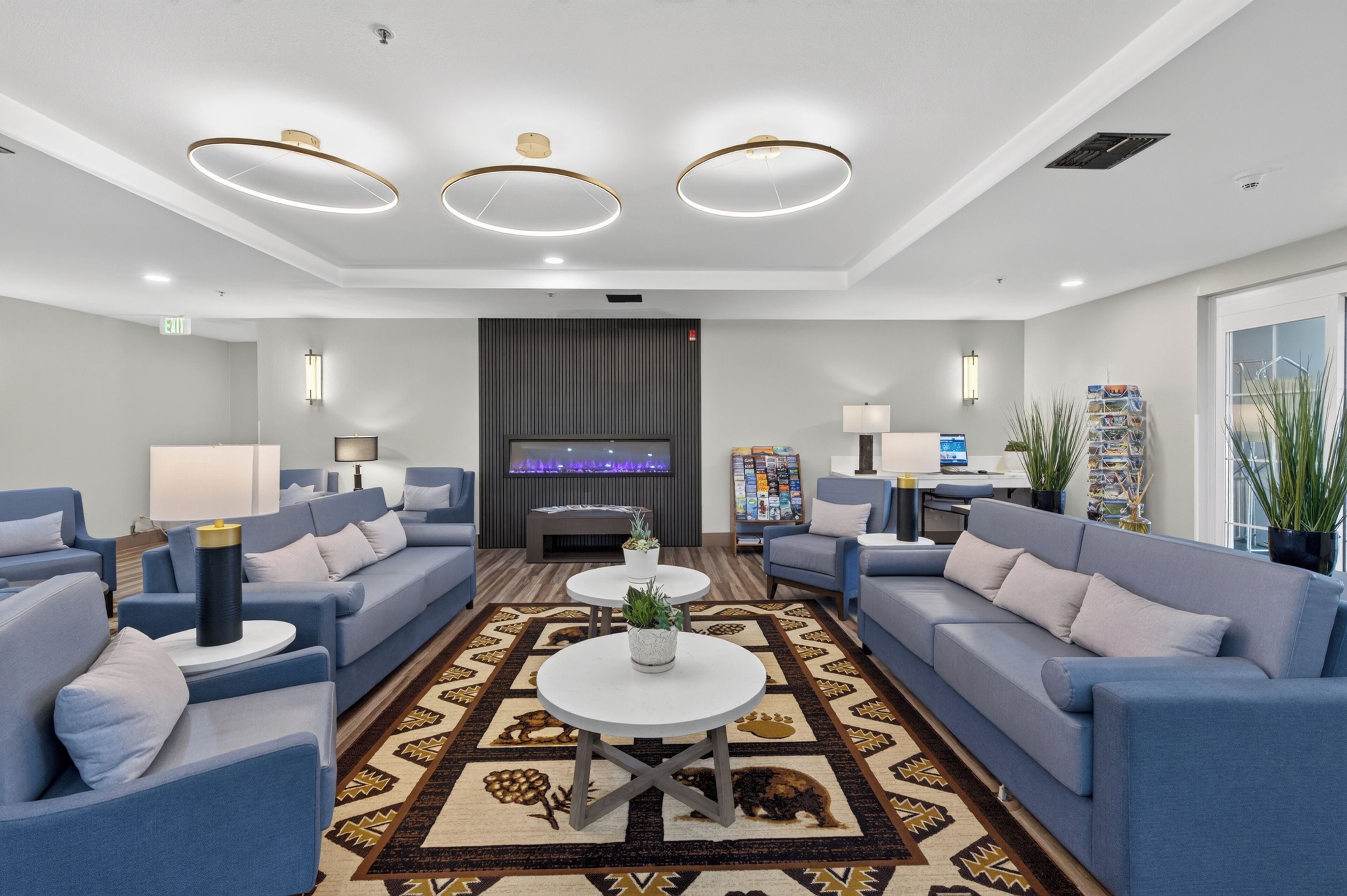 Un hall d’hôtel moderne avec des canapés, une table basse, un téléviseur à écran plat et un tapis à motifs.