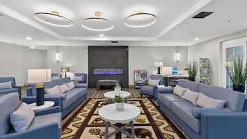 Un hall d’hôtel moderne avec des canapés, une table basse, un téléviseur à écran plat et un tapis à motifs.