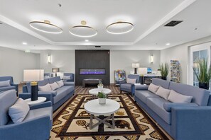 Een moderne hotel lobby met banken, een bijzettafeltje, een flatscreen televisie en een kamerbreed tapijt met dessin.