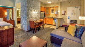Habitación de hotel con cama, escritorio, sofá, mesa de comedor y kitchenette.