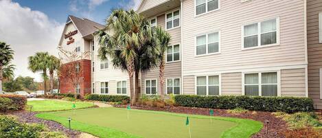 A hotel with a well-maintained lawn and a golf course.