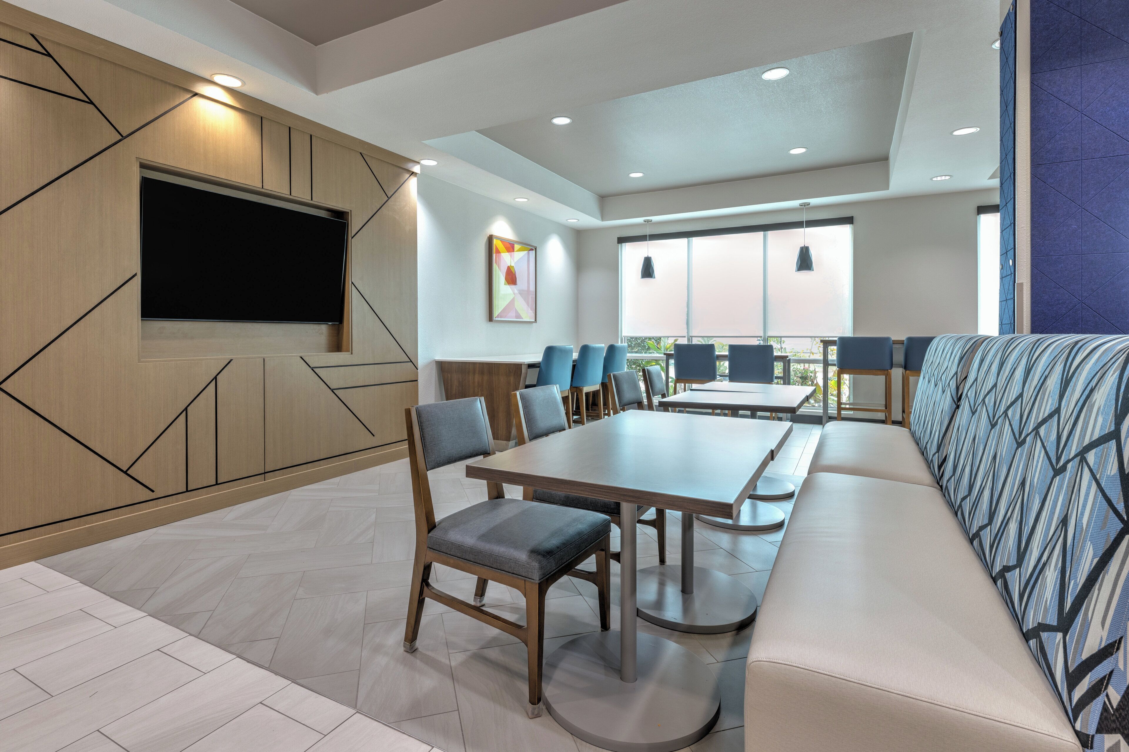A modern dining area with a long table, multiple chairs, and a sofa.