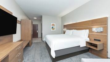 Ein modernes Hotelzimmer mit einem großen Bett, Holzmöbeln, einem Flachbildfernseher und einer wandmontierten Leuchte.