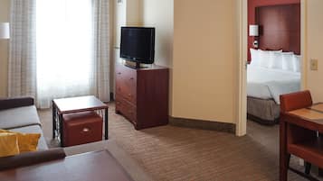 Ett hotellrum med en säng, en tv-apparat på en byrå i trä, en soffa, ett litet bord och ett golv täckt av matta.
