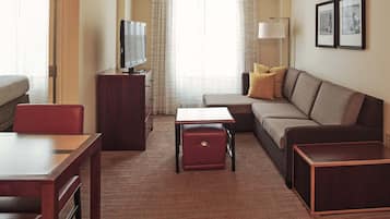 Una habitación de hotel con sofá, una mesita, televisión y lámpara.