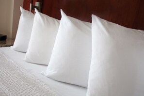 A neatly made bed with white linens and pillows.