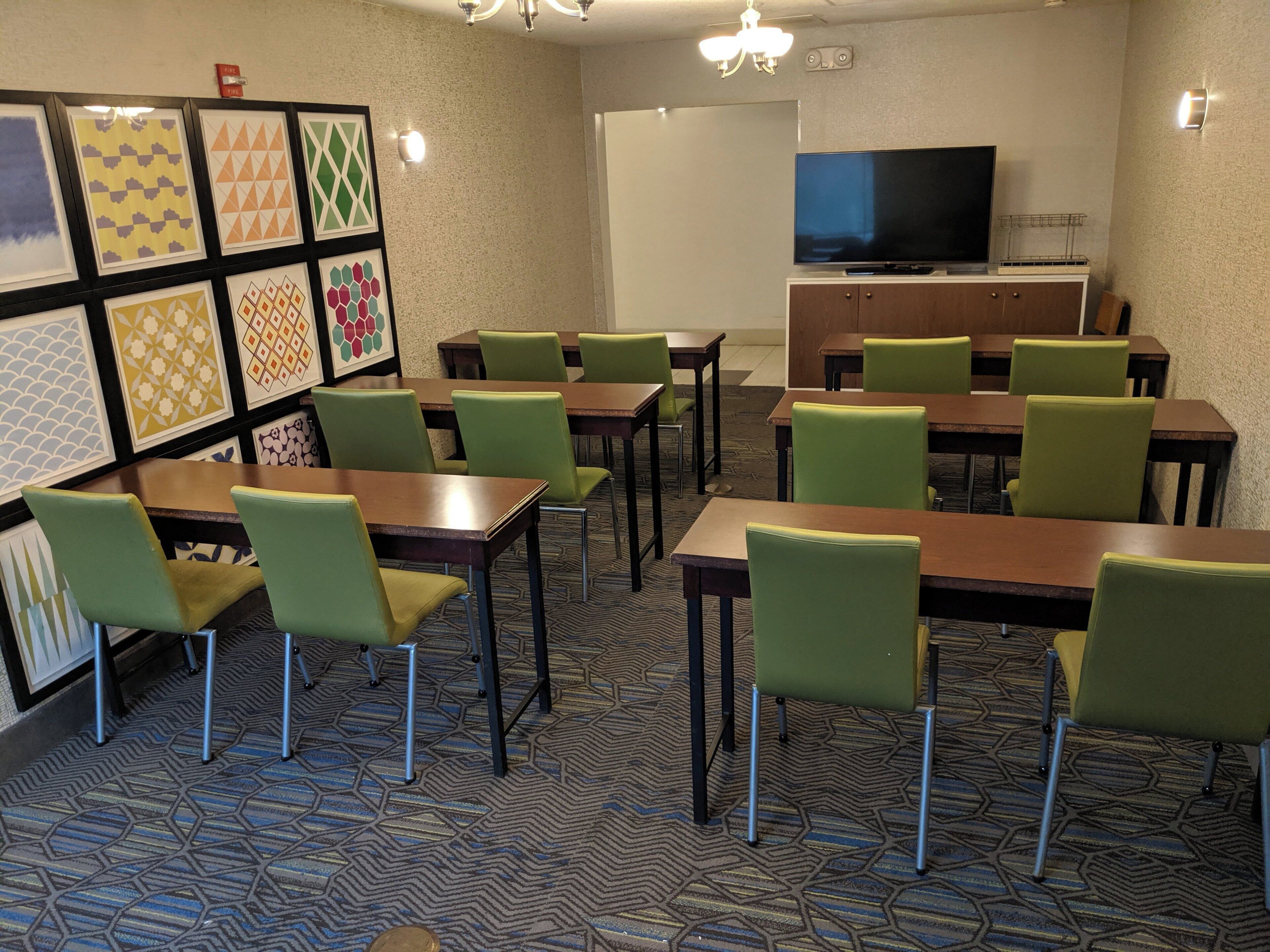 A conference room with tables and chairs, a television, and framed wall art.