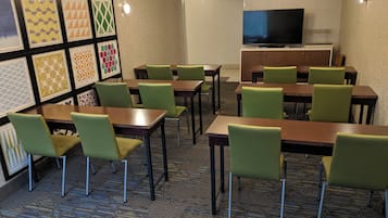 A conference room with tables and chairs, a television, and framed wall art.