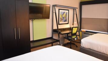 Een hotelkamer met een bed, een bureau met stoel, een televisie en een kledingkast.