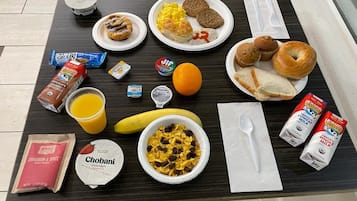 Una mesa de desayuno con diversos alimentos y bebidas, incluyendo yogur Chobani, leche orgánica Horizon y un plátano.