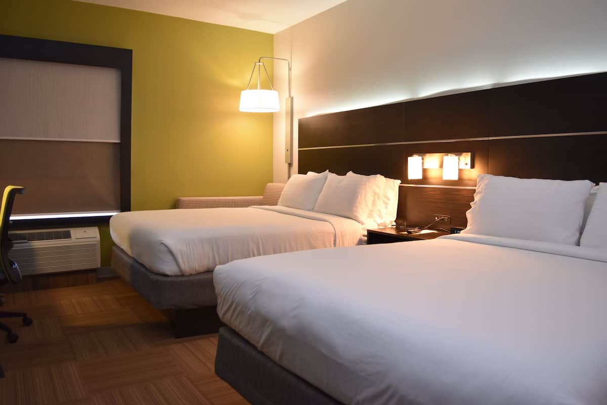 A hotel room with two beds, a desk, and a chair.
