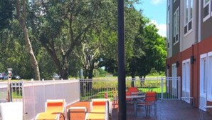 A swimming pool with lounge chairs and a table, surrounded by a fenced area with trees. - Holiday Inn Express Venice by IHG (Venice)