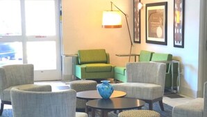 A room with four armchairs, a coffee table, and a lamp. There are framed pictures on the wall and a door leading outside. - Holiday Inn Express Venice by IHG (Venice)
