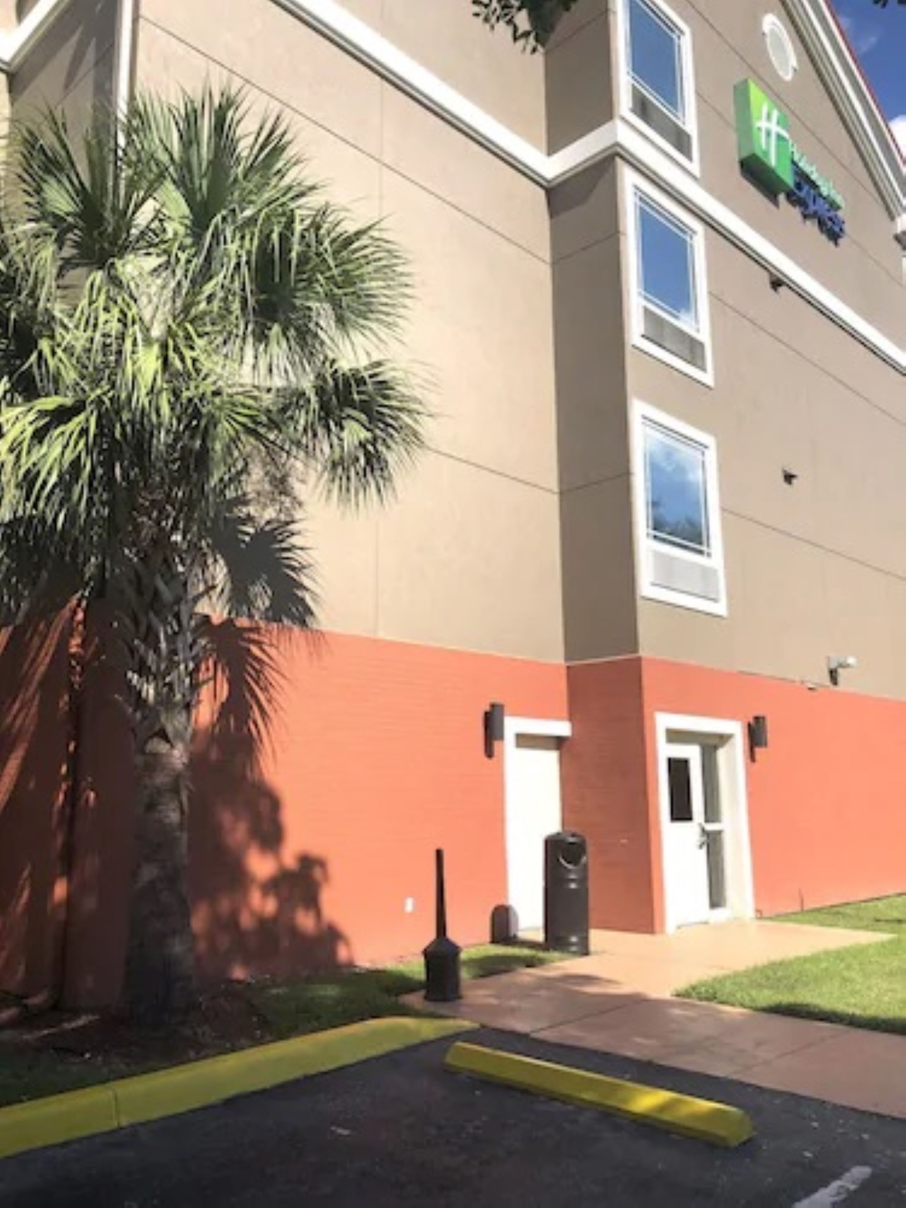 A building with a beige exterior and a green sign.