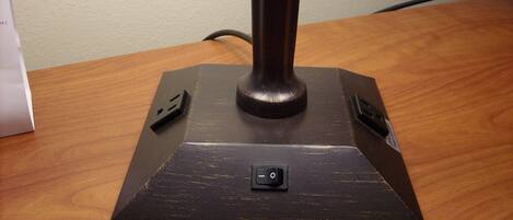 Une lampe de bureau avec un interrupteur, posée sur une table en bois.