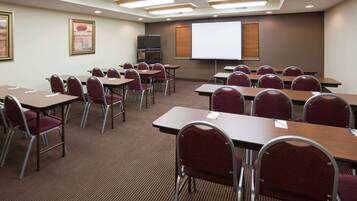 A conference room with tables and chairs, a projector screen, and a television.