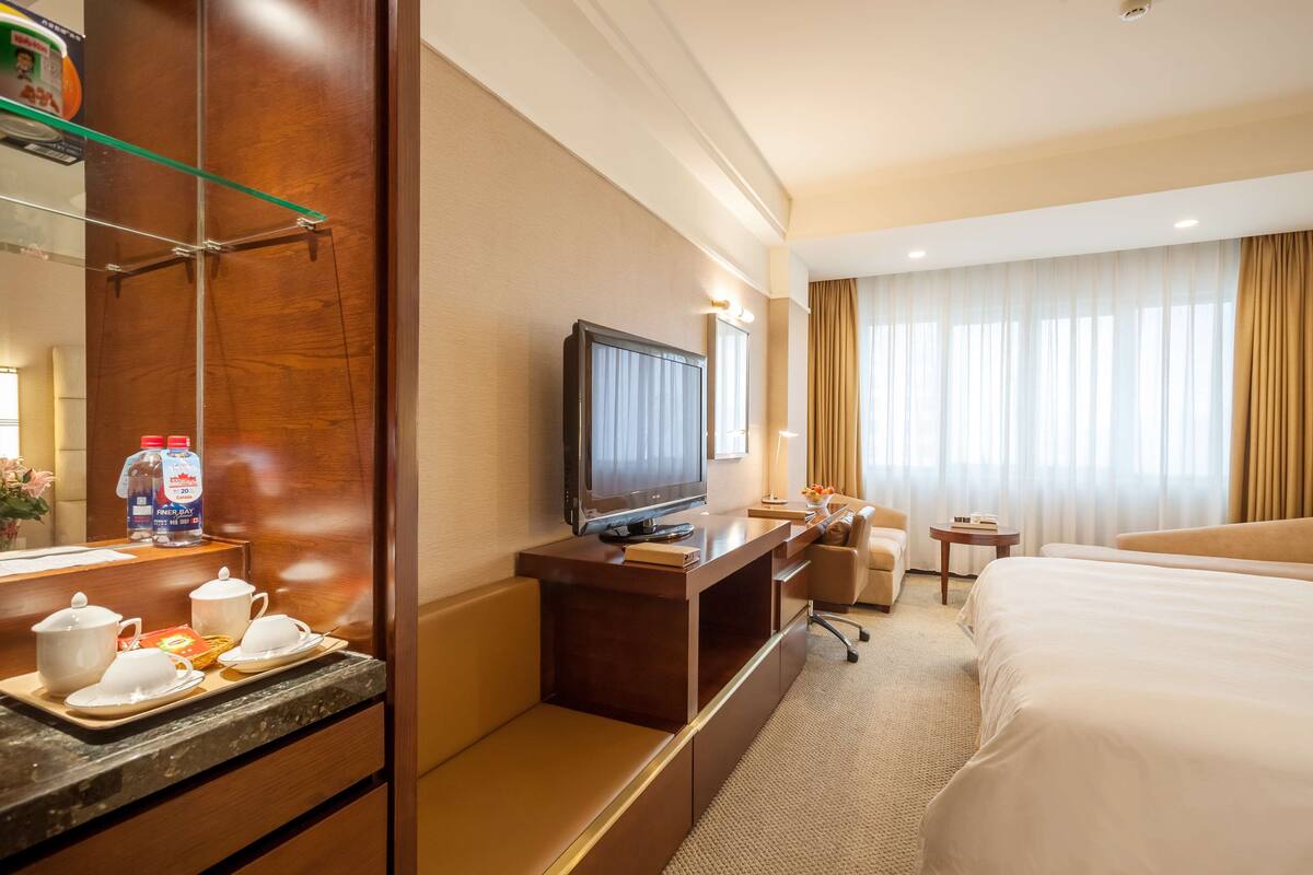 Une chambre d’hôtel comprenant un lit, un bureau avec une télévision, une petite table et un coin salon.