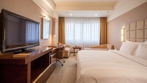A hotel room with a large bed, a desk with a flat-screen TV, a chair, a small table, and a window with curtains. - Best Western Plus Fuzhou Fortune Hotel (Fuzhou)