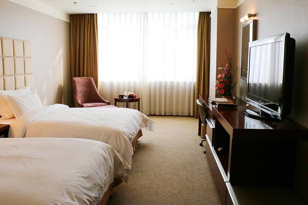 Une chambre d’hôtel avec deux lits, une télévision, un bureau et une chaise.