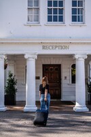 Un edificio con área de recepción, columnas blancas y puerta de madera.