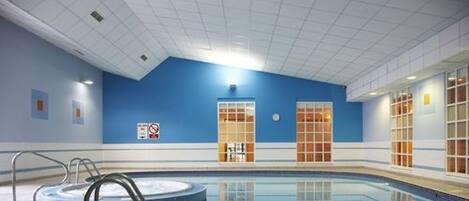 An indoor swimming pool with a blue wall, a hot tub, and a no swimming sign.